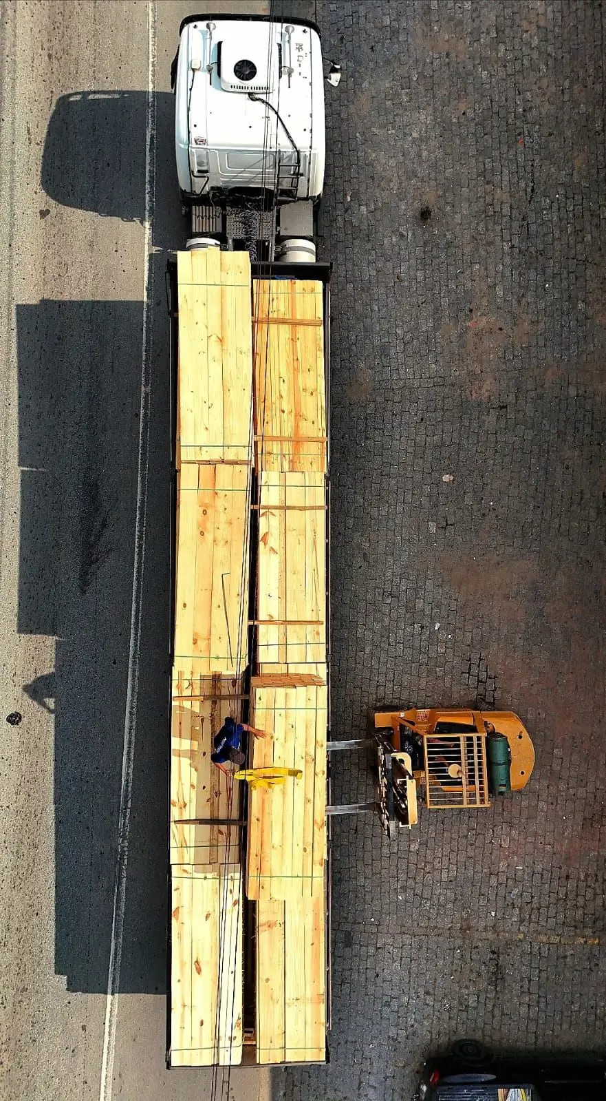 Caminhão sendo carregado com madeira